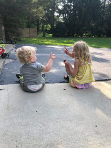Little boy and little girl sitting on the ground conversing.